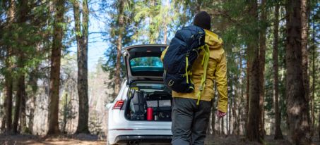 man in wood with hiking backpack going to car